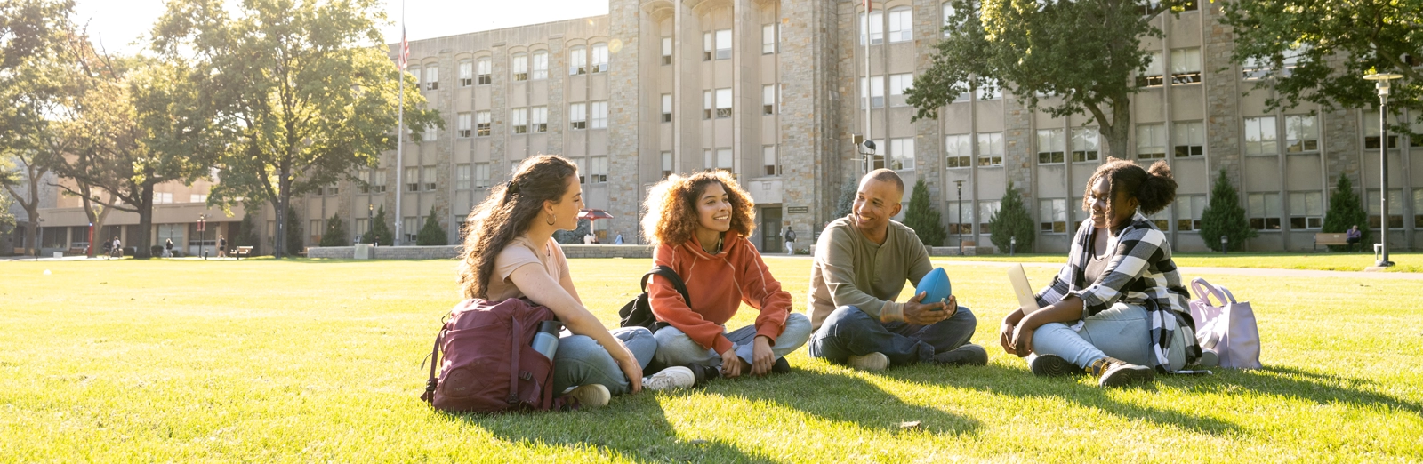 students-sitting-in-grass-outside-1600x522.webp